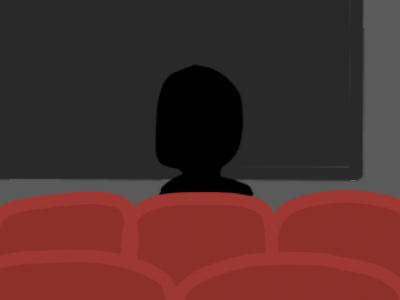 two people sitting in a movie theater facing the screen