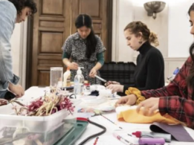 four students making dolls at a table filled with creative supplies