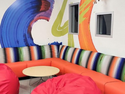colorful lounge with beanbag chairs, sofa, and C4C painted on wall