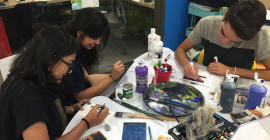 three students painting and drawing